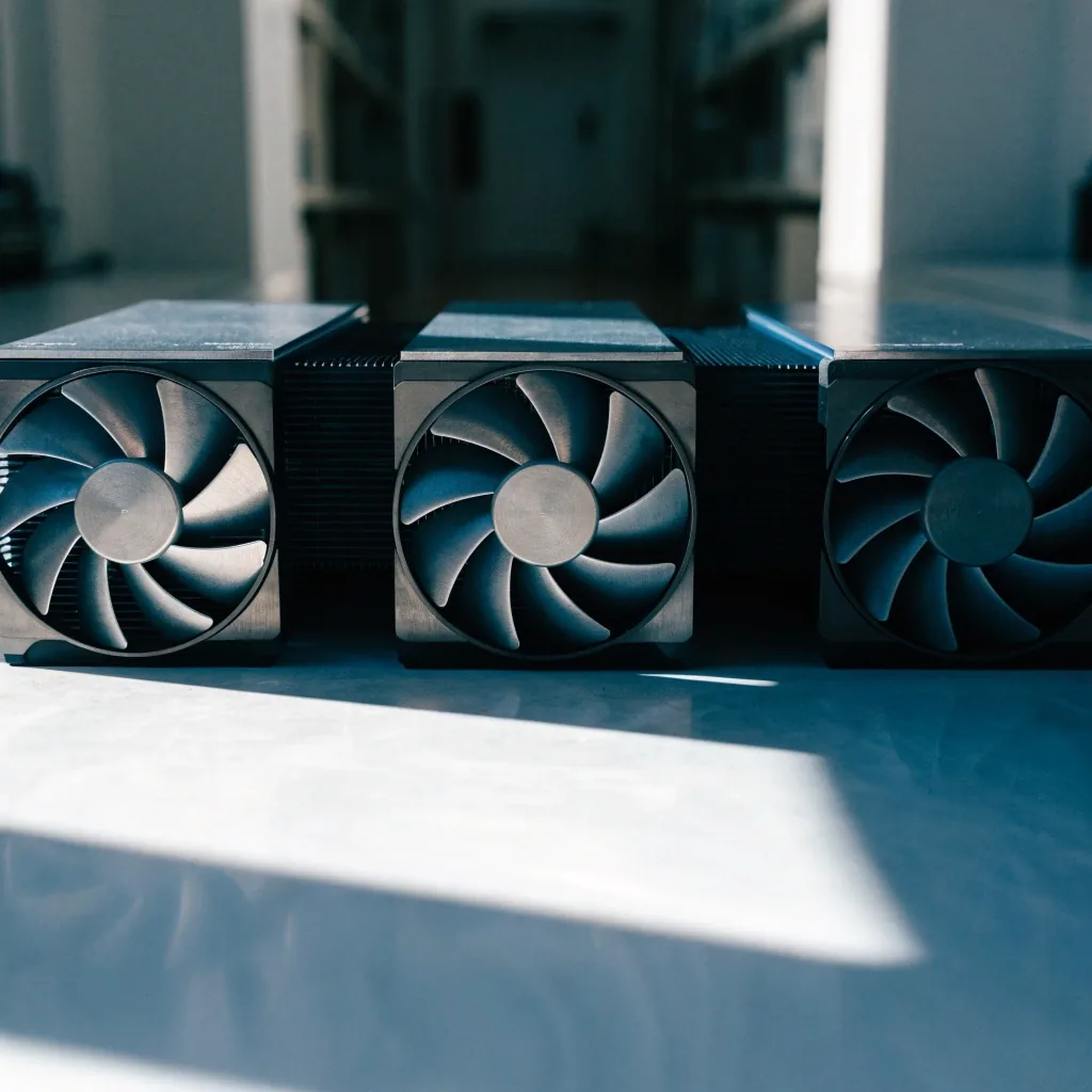 Three current-generation graphics cards lined up on a pale bench under hard daylight, seen at bench level
