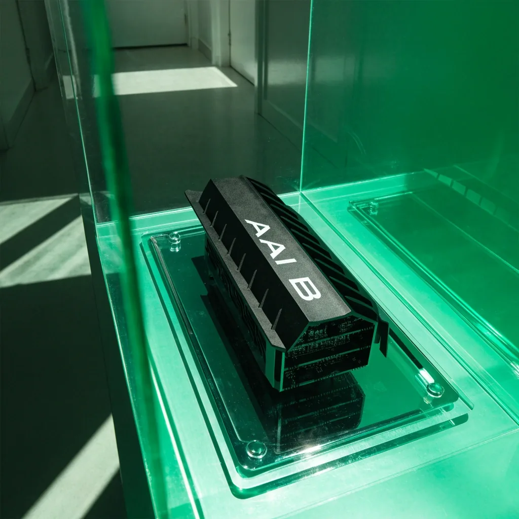 Flagship graphics card on a chrome tray inside a lit acrylic shelf, noon light raking the shroud